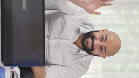 Vertical-video-of-Home-office-worker-man-waving-at-camera.